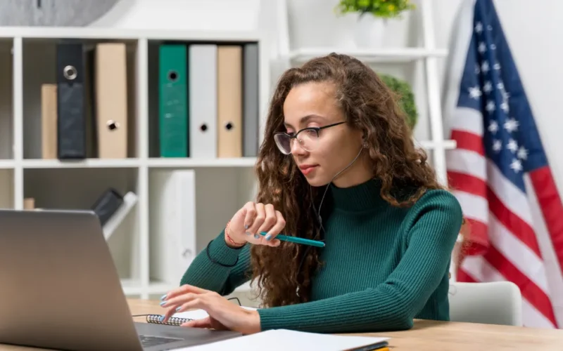 Pessoa sorrindo usando fones de ouvido em frente a um laptop, simbolizando aprendizado de inglês online com certificado