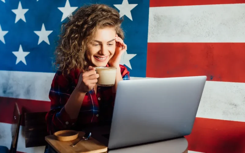 Pessoa digitando um e-mail profissional em inglês em um laptop, com ícones de comunicação e ferramentas de correção ao fundo.