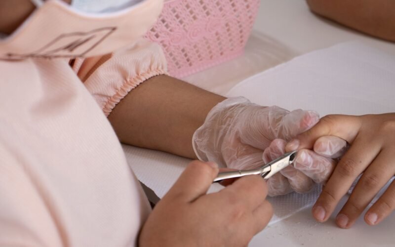 Manicure profissional realizando cutilagem perfeita com ferramentas esterilizadas em um salão de beleza